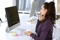 Business woman using phone and computer at workplace in modern office. Brunette secretary or female lawyer smiling and Royalty Free Stock Photo