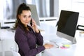 Business woman using phone and computer at workplace in modern office. Brunette secretary or female lawyer smiling and Royalty Free Stock Photo