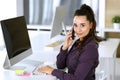 Business woman using phone and computer at workplace in modern office. Brunette secretary or female lawyer smiling and Royalty Free Stock Photo