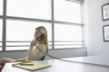 Business woman using phone sitting at office desk side view Royalty Free Stock Photo