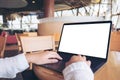 Business woman using and typing on laptop with blank white desktop screen in cafe Royalty Free Stock Photo