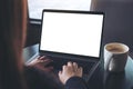 Business woman using and typing on laptop with blank white screen and coffee cup on table in cafe Royalty Free Stock Photo