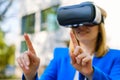 Business woman using VR goggles touching the simulation screen in the park