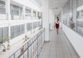 Business Woman Walking Along the Office Corridor. Smiling Businesswoman Goes Against White Offices Background. A young pretty girl