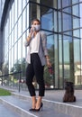 Business woman walking dog on leash and talking on phone Royalty Free Stock Photo