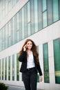 Business woman walks outdoor with smartphone talking to her team Royalty Free Stock Photo