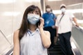 Business woman wearing face mask at train station and talking on the phone Royalty Free Stock Photo