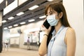 Business woman wearing face mask at train station watching the mobile phone Royalty Free Stock Photo