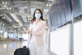 A business woman is wearing protective mask in International airport, travel under Covid-19 pandemic, safety travels, social