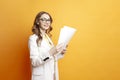 business woman in white suit holding documents on orange isolated background, girl manager in glasses with papers Royalty Free Stock Photo