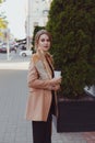 Business woman in a rush, carrying baguettes and takeaway hot beverage. Street portrait, back view.