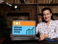 Business woman at work with financial reports EMS EUROPEAN MONETARY SYSTEM and a laptop