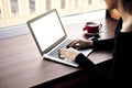 Business woman working in laptop computer, drinking cappuccino in coffee shop