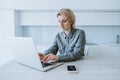 Business woman working at a laptop while sitting at a table in a bright office Royalty Free Stock Photo