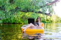 Business woman working on a laptop and talking on smartphone in an inflatable ring in the water, a copy of the free space. Royalty Free Stock Photo