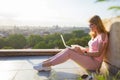 Woman working with laptop on terrace overlooking city