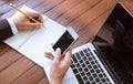 Business woman write on notebook and use cell phone working outdoor in coffee shop vintage tone Royalty Free Stock Photo