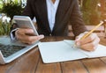 Business woman write on notebook and use cell phone working outdoor in coffee shop vintage tone Royalty Free Stock Photo