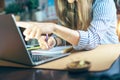 Business woman writes in notebook on desk and pointing hand at computer screen. Girl working from home office kithcen. Using Royalty Free Stock Photo