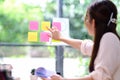 Businesswoman writing creative ideas on sticky notes on glass wall in modern office. Royalty Free Stock Photo