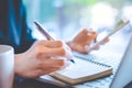 Business women hand are working at a notebook computer and taking notes in a pen notepad in the office.Soft focus Royalty Free Stock Photo