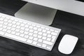 Business workplace with computer, wireless keyboard and mouse on black wooden table background. Office desk with copy space. Royalty Free Stock Photo