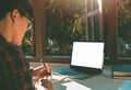 Business young man hands holding pen writing notebook and using a laptop white blank screen on desk at the home Royalty Free Stock Photo