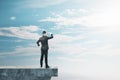 Businessman on abstract concrete edge looking into the distance on creative bright sky background with mock up place. Future, Royalty Free Stock Photo