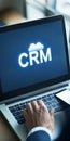 Businessman Accessing Cloud-Based CRM System, CRM Text in Cloud Icon on Laptop Screen