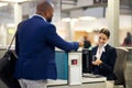 Businessman, airport and passenger assistant checking passport documents for check in at terminal counter. Black male Royalty Free Stock Photo