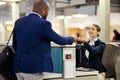 Businessman, airport and passenger assistant helping traveler with checkin at terminal counter. Black male with passport Royalty Free Stock Photo
