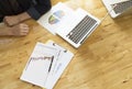 Businessman analyze data from business report chart. Top view of wooden working desktop with labtop.