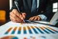 Businessman analyzing financial data and charts with a pen and laptop in an office setting Royalty Free Stock Photo