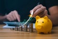 Businessman analyzing forex trading graph financial data. coin in a piggy bank and arrows showing charts on his desk. Royalty Free Stock Photo