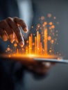 Businessman analyzing interactive glowing orange digital data charts emerging from a tablet in modern technology concept for Royalty Free Stock Photo