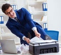 Businessman angry at copying machine jamming papers Royalty Free Stock Photo