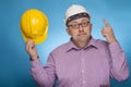 A businessman, architect in a piked shirt pointing with the index finger on the white hard hat