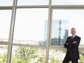 Businessman With Arms Crossed Standing By Office Window Royalty Free Stock Photo