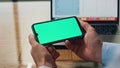 Businessman arms holding mockup smartphone indoors. Boss using green display