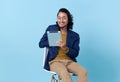 Businessman asian happy smiling using a digital tablet while sitting on chair isolated on bright blue background Royalty Free Stock Photo