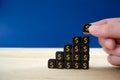 Businessman assembling black dices with gold dollar signs in a shape of growth graph