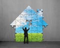 Businessman assembling house shape puzzles with beautiful landscape Royalty Free Stock Photo