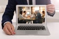 Businessman attending online video conference via modern laptop at table in office Royalty Free Stock Photo