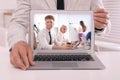 Businessman attending online video conference via laptop at table in office, closeup Royalty Free Stock Photo