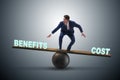 Businessman balancing between cost and benefit in business conce Royalty Free Stock Photo