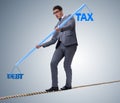 Businessman balancing between debt and tax Royalty Free Stock Photo