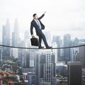 Businessman balancing on a string over the city, city view with scyscrapers in the background. Risk and self confidence concept Royalty Free Stock Photo