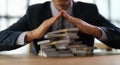 Businessman banker making roof over stacks of money with hands closeup