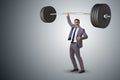 The businessman with barbell in heavy lifting concept