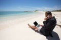Businessman on the beach working with computer and speaking on phone Royalty Free Stock Photo